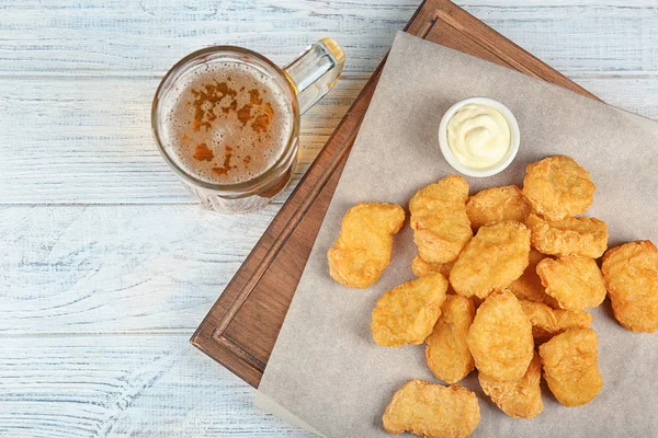 Tasty chicken nuggets i szklankę piwa na stole — Zdjęcie stockowe