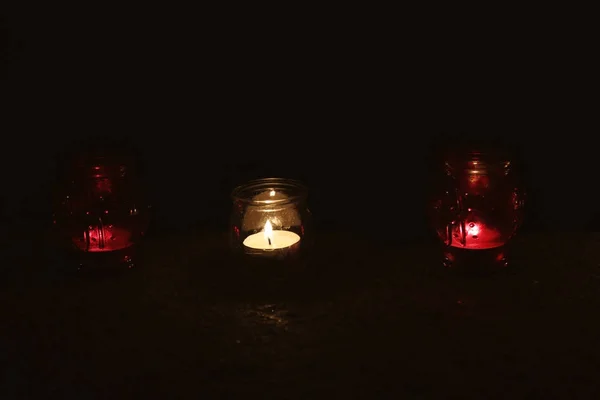 Frascos con velas encendidas en la superficie de piedra en la oscuridad — Foto de Stock