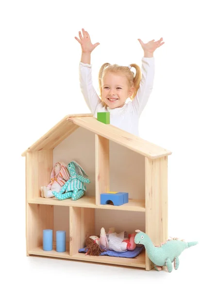 Мила дівчинка грає з дерев'яним ляльковим будиночком на білому тлі — стокове фото