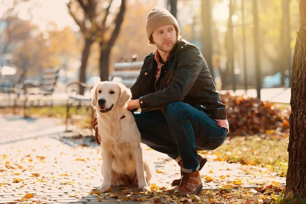 Handsome young hipster with dog outdoors — Stock Photo, Image