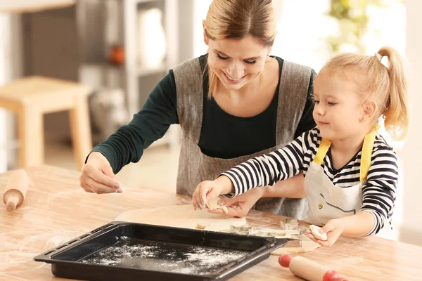 Mother and daughter with dough at table indoors — Stock Photo, Image