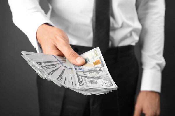 Businessman holding money on dark background. Corruption concept
