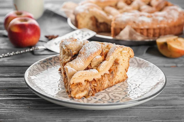Тарелка с кусочком вкусного яблочного пирога на деревянном столе — стоковое фото