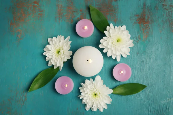 Beautiful composition with flowers and burning candles on wooden background — Stock Photo, Image