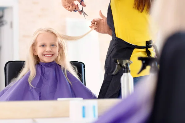Женщина-парикмахер работает с маленькой девочкой в салоне — стоковое фото