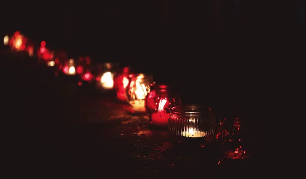 Frascos con velas encendidas en la superficie de piedra en la oscuridad — Foto de Stock