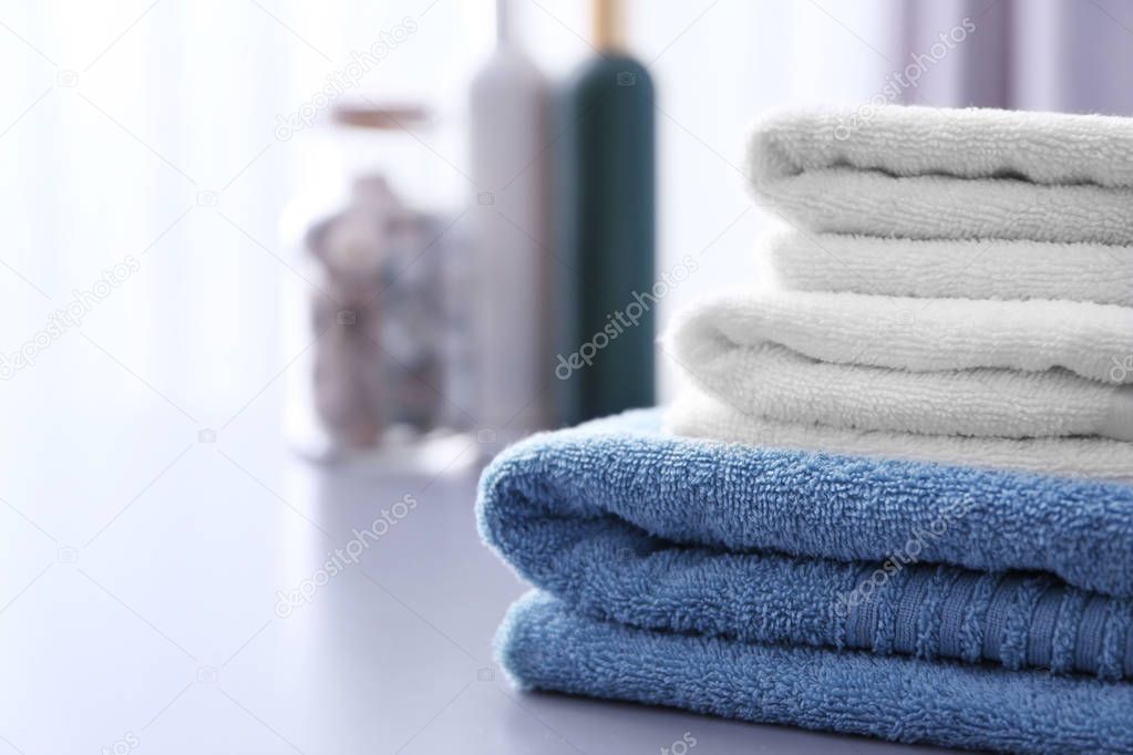Stack of clean towels on table in bathroom