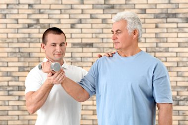 Fizyoterapist tuğla duvar arka plan üzerinde hasta ile çalışma