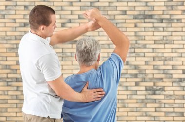 Fizyoterapist tuğla duvar arka plan üzerinde hasta ile çalışma