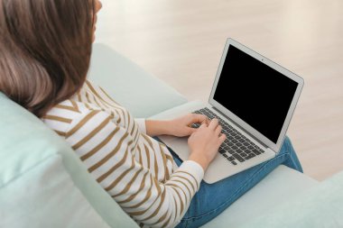 Modern dizüstü evde koltukta oturan genç kadınla