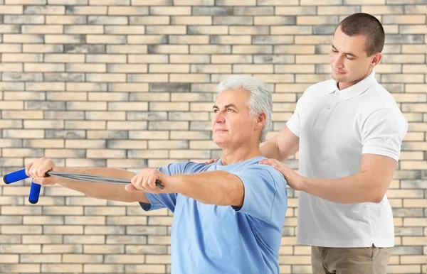 Physiotherapist working with patient on brick wall background — Stock Photo, Image