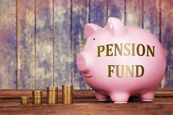 Prasátko s textem penzijní fond a mince na dřevěný stůl — Stock fotografie