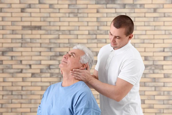 Fisioterapeuta trabajando con paciente sobre fondo de pared de ladrillo —  Fotos de Stock