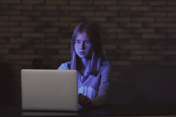 暗い部屋でノート パソコンのそばに座って悲しいの十代の少女 — ストック写真