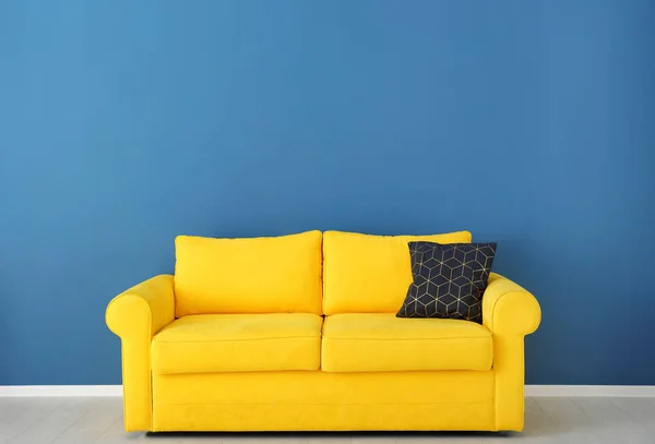 Bright yellow couch near color wall