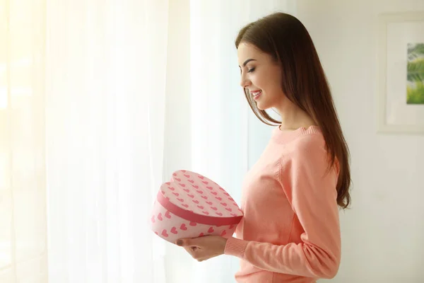 Schöne junge Frau hält Geschenkbox zu Hause — Stockfoto
