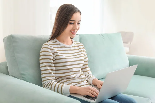 Młoda kobieta z nowoczesnym laptopie siedzi na kanapie w domu — Zdjęcie stockowe