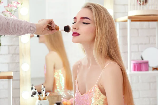 Artista profesional creando maquillaje para hermosa modelo en la habitación — Foto de Stock