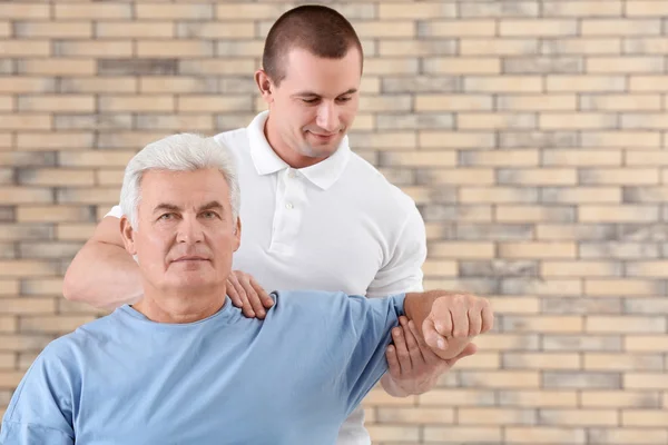 Fyzioterapeut se s pacientem na cihlovou zeď na pozadí — Stock fotografie