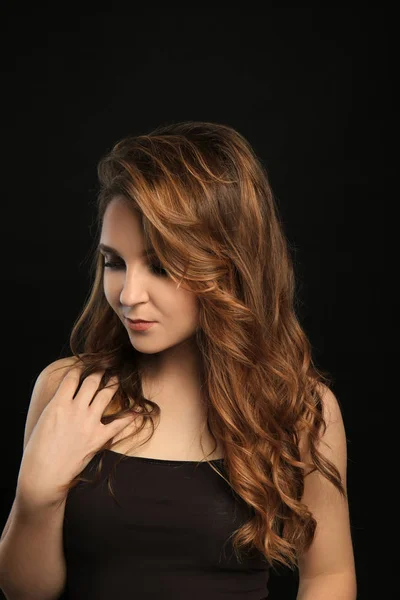 Attractive young woman with caramel highlights on black background — Stock Photo, Image