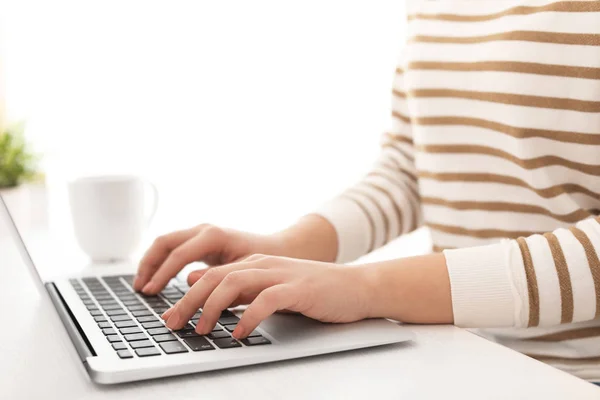 Jonge vrouw die werkt met moderne laptop op tafel, close-up — Stockfoto