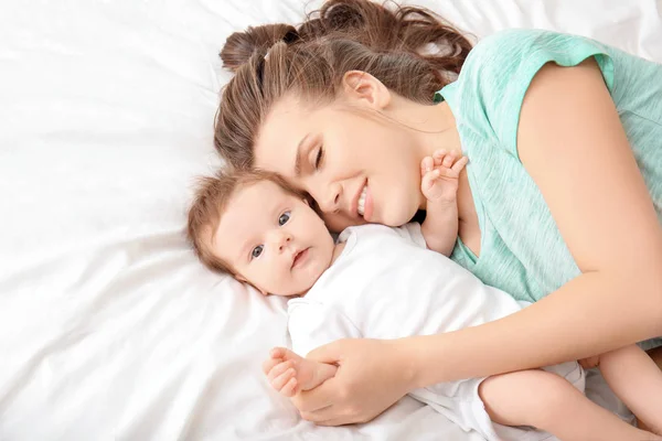 Joven madre y lindo bebé en la cama en casa — Foto de Stock