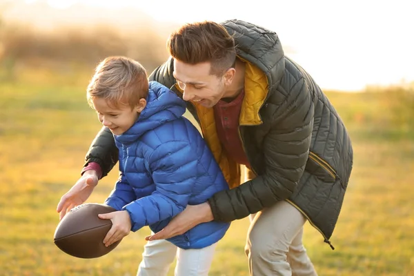 Açık havada rugby oynayan küçük oğluyla baba