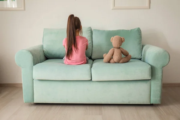 Dziewczynka z misiem, siedząc na kanapie w domu. Autyzm dziecko — Zdjęcie stockowe