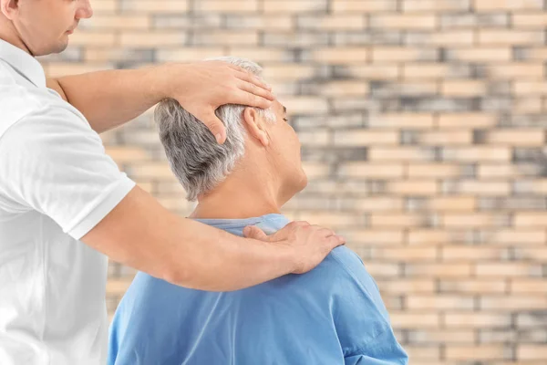 Fisioterapeuta trabajando con paciente sobre fondo de pared de ladrillo — Foto de Stock