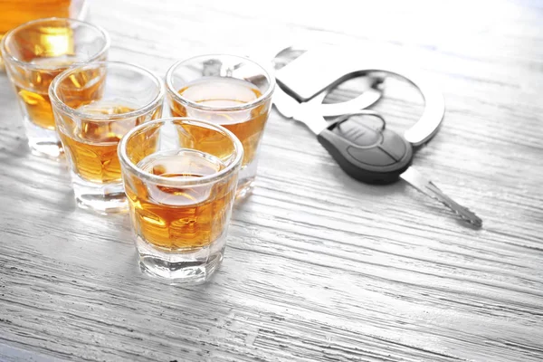 लकड़ी की मेज पर हैंडकाफ और कार कुंजी के साथ शराब का चश्मा। पेय और ड्राइव अवधारणा मत करो — स्टॉक फ़ोटो, इमेज