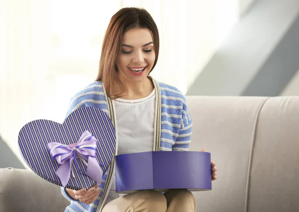 Wanita muda cantik membuka kotak hadiah di rumah — Stok Foto