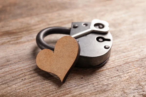 Composition with lock, key and heart on wooden background