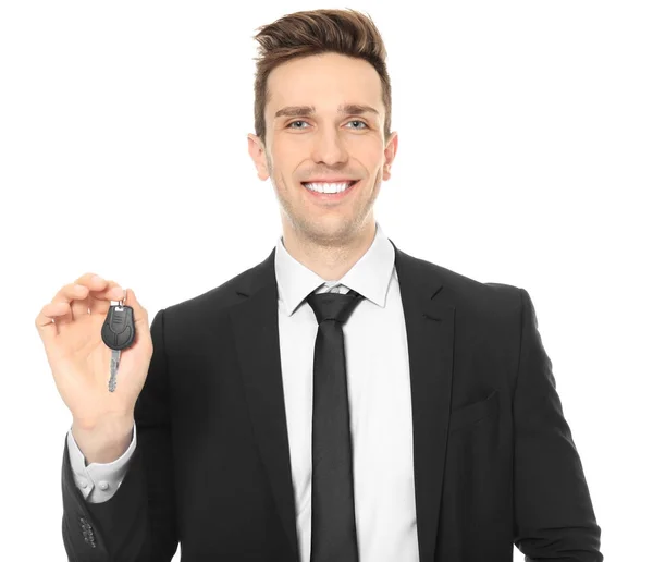 Young salesman holding car key on white background — Stock Photo, Image