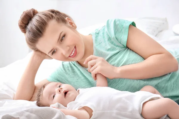 Jovem mãe e bebê bonito na cama em casa — Fotografia de Stock