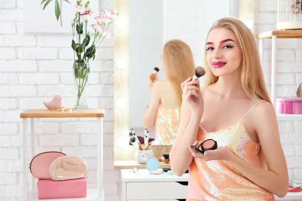 Junge schöne Frau schminkt sich in der Nähe von Spiegel im Zimmer — Stockfoto