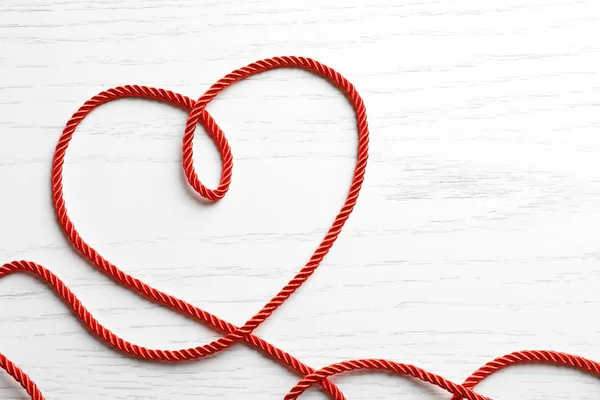 白い木製の背景に赤いロープの作られた心 — ストック写真