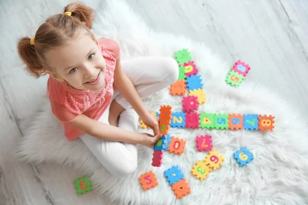 Милая маленькая девочка, играющая с паззлами дома — стоковое фото