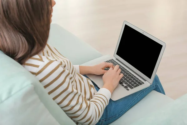 Νεαρή γυναίκα με σύγχρονο φορητό υπολογιστή που κάθεται στον καναπέ στο σπίτι — Φωτογραφία Αρχείου