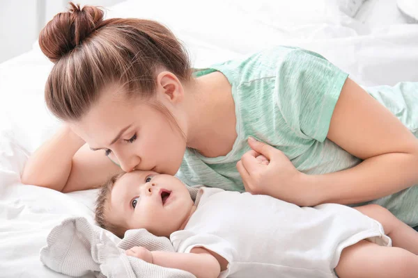 Jovem mãe e bebê bonito na cama em casa — Fotografia de Stock