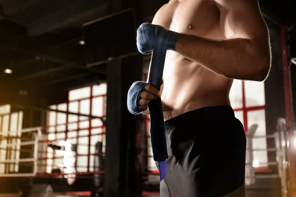 Boxeador masculino que aplica envolturas de mano mientras se prepara para el entrenamiento en gimnasio — Foto de Stock