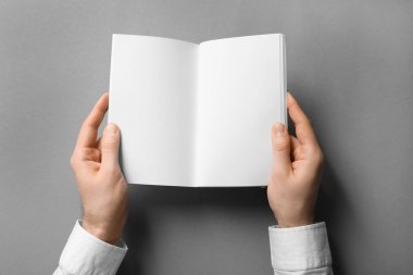 Boş sayfaları ile kitapçık gri arka plan üzerinde tutan adam. Tasarım için alay