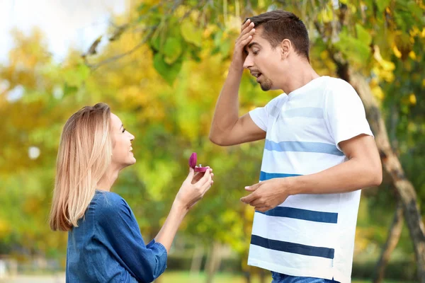 Mujer joven con anillo de compromiso haciendo propuesta de matrimonio a su novio en el parque — Foto de Stock
