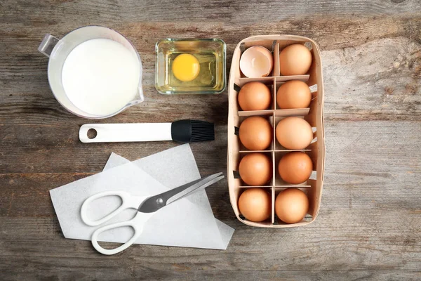 Kitchen utensils and ingredients for pastries on wooden background