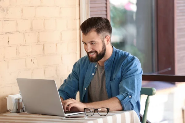 Joven blogger usando laptop en cafetería al aire libre —  Fotos de Stock