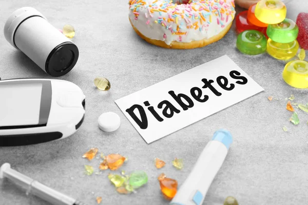 Composition with word "Diabetes", glucometer, medicaments and treats on grey background — Stock Photo, Image