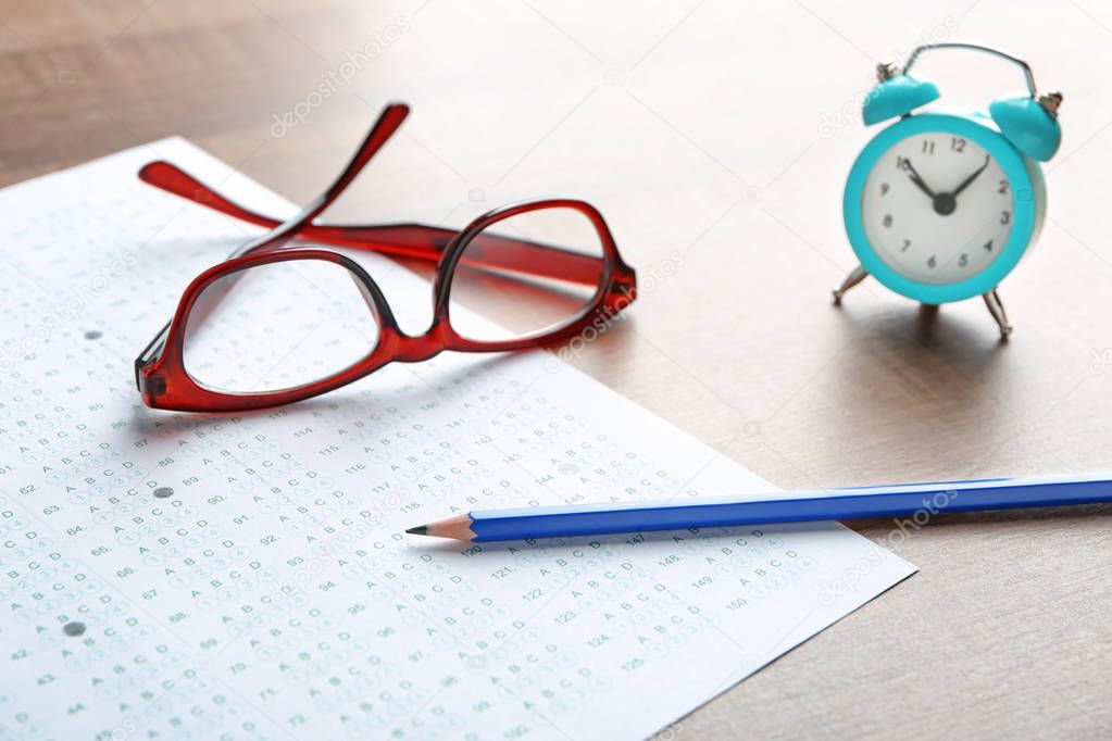 Exam form, pencil and student's eyeglasses on table