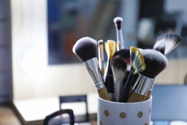 Farklı fırçalar ile fincan bulanık arka plan üzerinde profesyonel makyaj sanatçısı