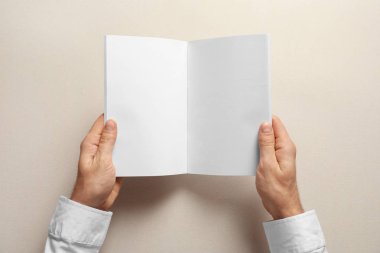 Broşür boş sayfaları ile ışık arka plan üzerinde tutan adam. Tasarım için alay