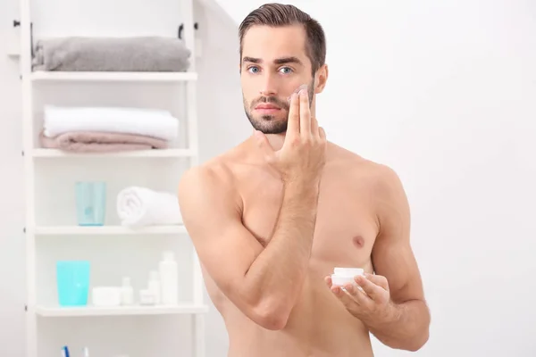 Mladý Pohledný Muž Používání Krému Obličej Koupelně — Stock fotografie