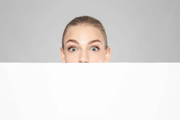 情感年轻妇女与空白的广告板在灰色背景 — 图库照片